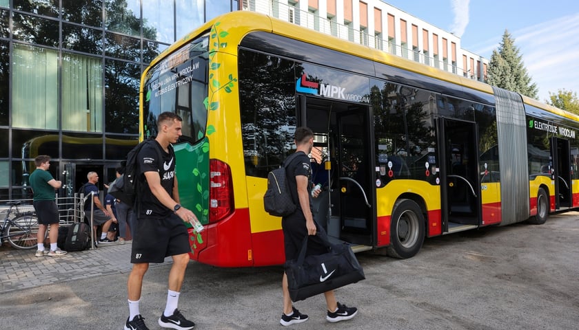 Dwaj mężczyźni przed autobusem miejskim (zdjęcie ilustracyjne)