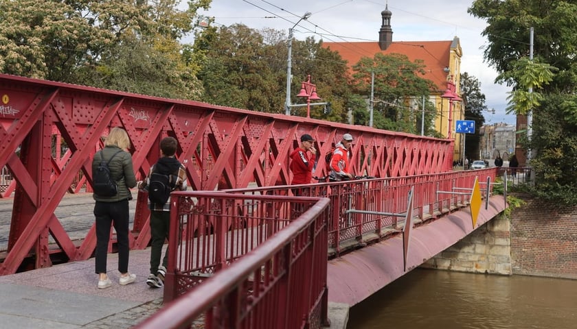 Ludzie na moście patrzą na Odrę we Wrocławiu 