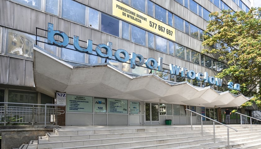 Fragment fasady biurowca Budopolu z zygzakowatym dachem nad wejściem głównym