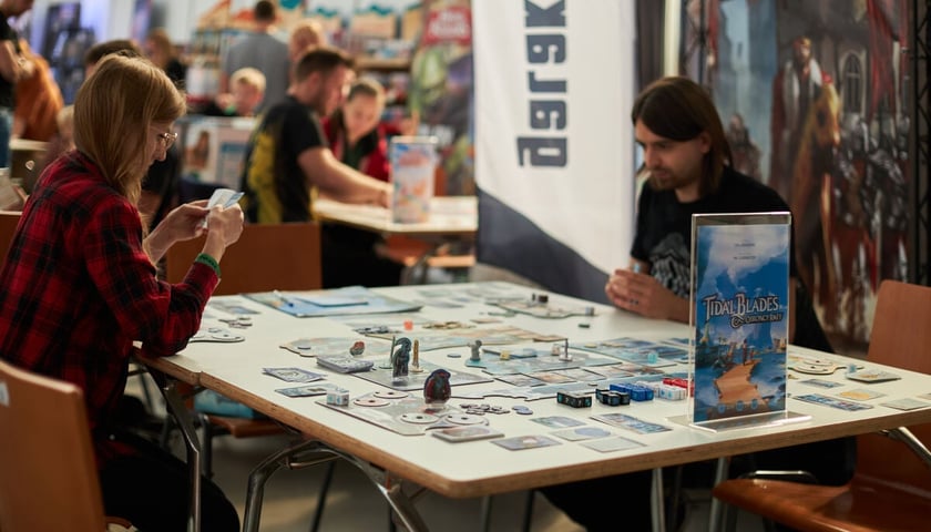 Dwójka graczy przy stoliku z planszówką. Zdjęcie ilustracyjne, wykonane podczas Games Week w Hali Stulecia.