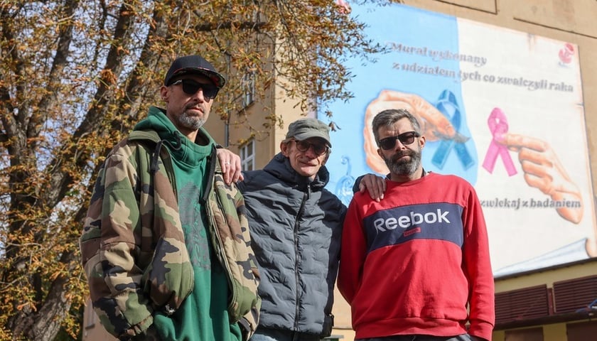 Na tle muralu stoją od lewej: Sebastian Szlachetka, Wojtek Miszewski i Mariusz Sahe