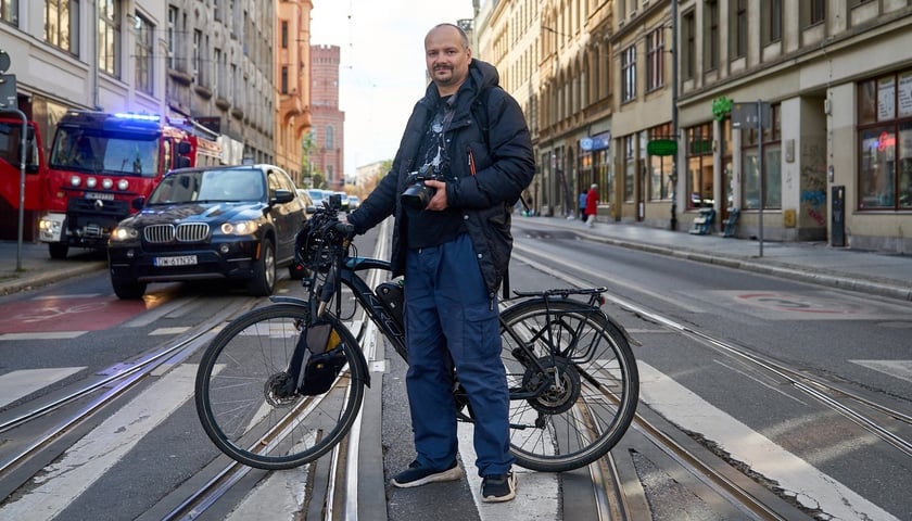 Mężczyzna z rowerem na przejściu dla pieszych, w tle samochody. Piotr Herba pomysłodawca i twórca ogólnopolskiego serwisu fotopolska.eu. 