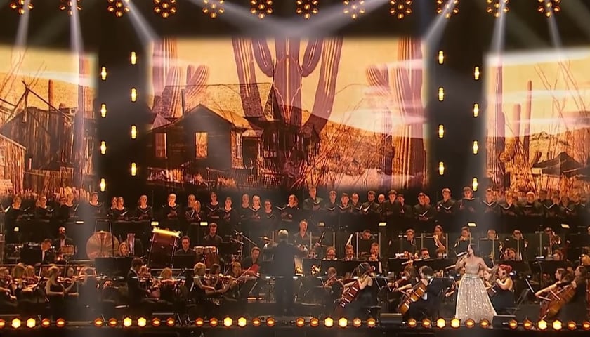 Na zdjęciu artyści na scenie, w tle ekran