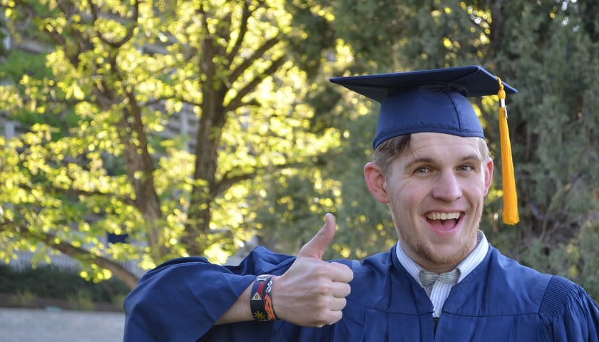 Student pokazuje kciuk do góry,  uśmiecha się