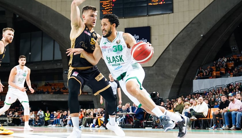 Jeremy Senglin (biały strój) kozłujący obok Jakuba Schenka (czarny strój) podczas meczu Śląska z Treflem w Hali Stulecia 