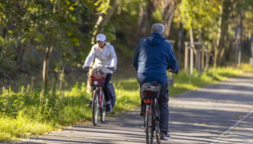 Dwie mijające się osoby na rowerach, ubrane w kurtki, na Promenadzie Krzyckiej 