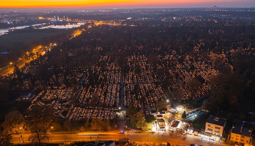 Palące się znicze na grobach na cmentarzu Osobowiskim, zmierzch, w tle most Milenijny i Odra, zdjęcia z drona w okresie Wszystkich Świętych 2024
