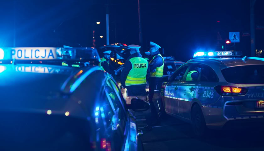 Radiowozy policji i grupa funkcjonariuszy - nocna akcja. Zdjęcie ilustracyjne