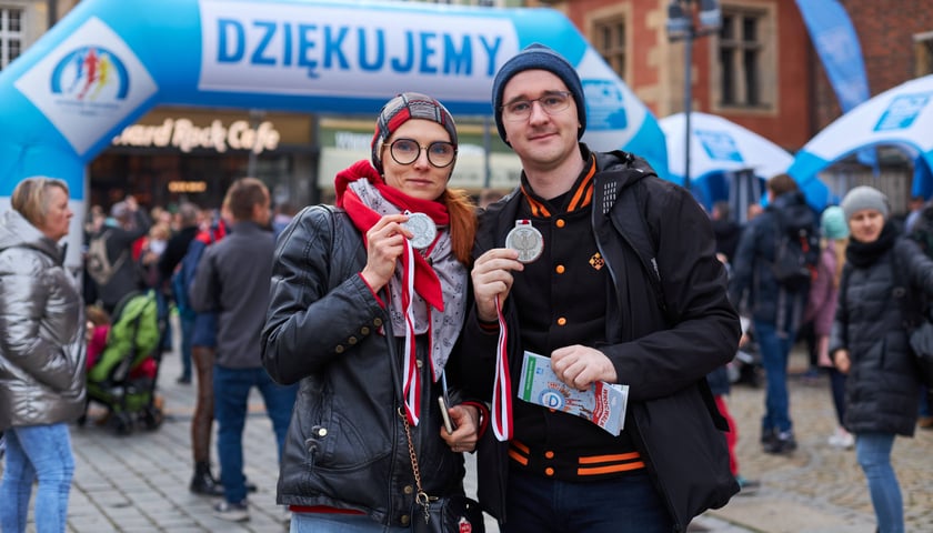 Kobieta i mężczyzna z medalami na tle mety z napisem dziękuję - WrocWalk 2023