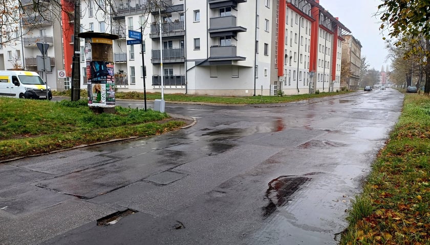 Zniszczona nawierzchnia ulicy Mościckiego do remontu, obok niej bloki