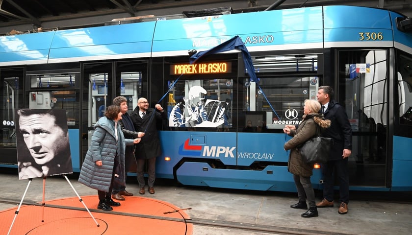Kilka osób odsłania nazwisko Marka Hłaski na tramwaju w zajezdni przy ul. Ślężnej (22 listopada 2024)