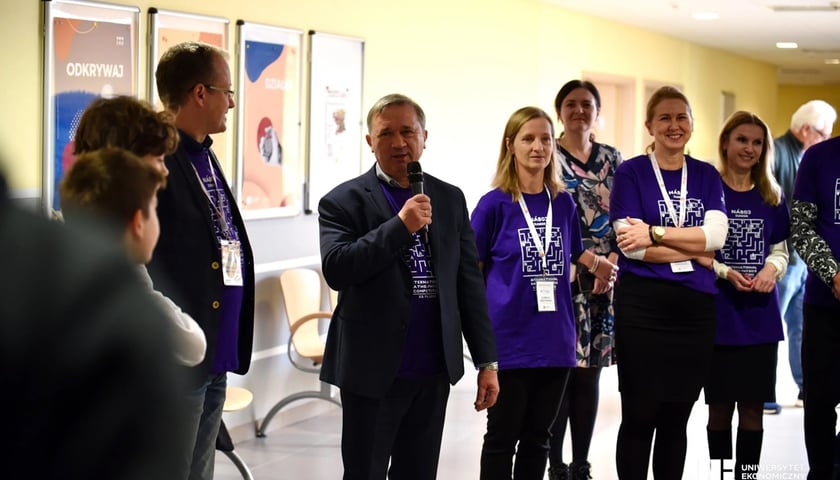 Prof. dr hab. Czesław Zając, rektor Uniwersytetu Ekonomicznego we Wrocławiu podczas inauguracji Náboj Junior we Wrocławiu. Na zdjęciu mężczyzna z mikrofonem w otoczeniu kilku osób