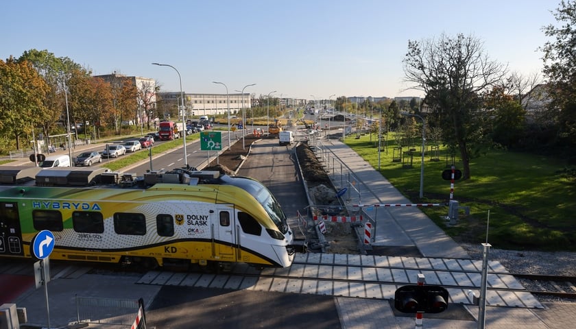 Widok z góry na ulicę Buforową z samochodami i przejeżdżający pociąg regionalny 