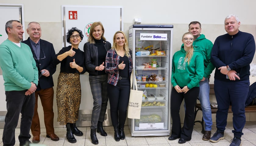 Grupa ludzi na tle nowej lodówki społecznej w centrum handlowym "Gaj".
