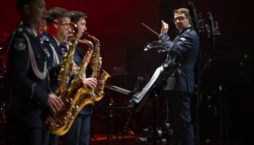 Koncert jubileuszowy Orkiestry Komendy Wojewódzkiej Policji we Wrocławiu w Narodowym Forum Muzyki we Wrocławiu. Na zdjęciu dyrygent oraz trzech saksofonistów podczas koncertu, wszyscy są w policyjnych mundurach