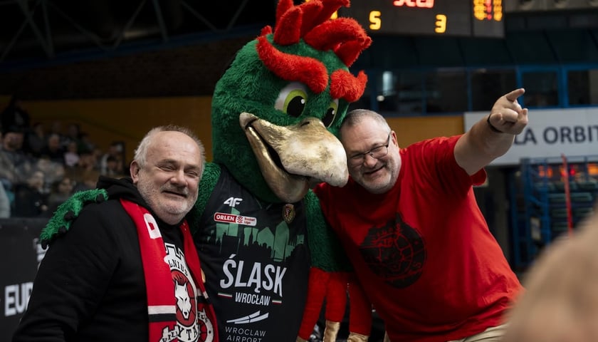 Mężczyźni i maskotka Śląska na trybunie Orbity podczas meczu Śląska z Rytasem