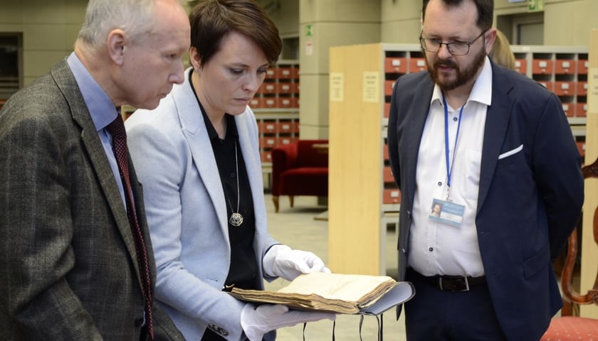 Na zdjęciu trzy osoby oglądają dokument. W środę: dr Dorota Siwecka, dyrektor Biblioteki Uniwersyteckiej we Wrocławiu, po lewej - dr Janusz Gołaszewski, dyrektor Archiwum Państwowe we Wrocławiu, z prawej dr Antoine Haaker, specjalista z Oddziału Rękopisów Biblioteki Uniwersyteckiej.