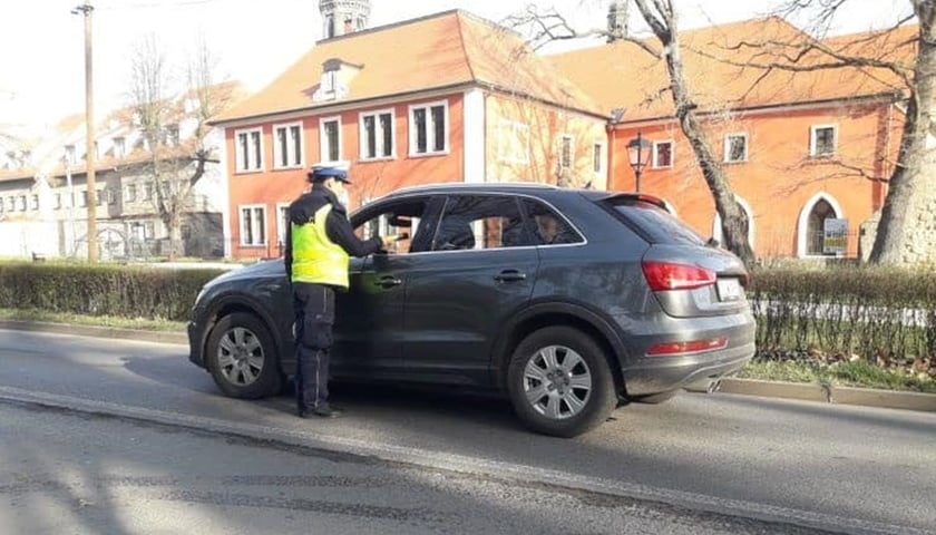 Na zdjęciu widać policjantkę w mundurze przy kontrolowanym samochodzie