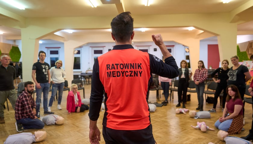 Ratownik medyczny w kamizelce odblaskowej prowadzący szkolenie o procedurach podtrzymujących życie