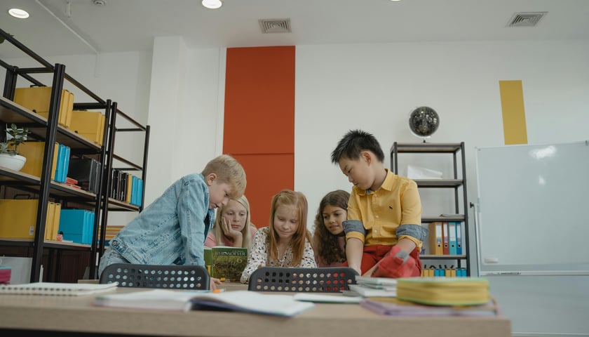 Kilkoro dzieci czyta wspólnie książkę