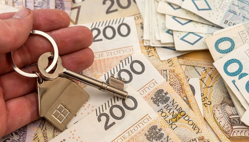 Banknoty a na nich klucze do mieszkania (zdjęcie ilustracyjne)