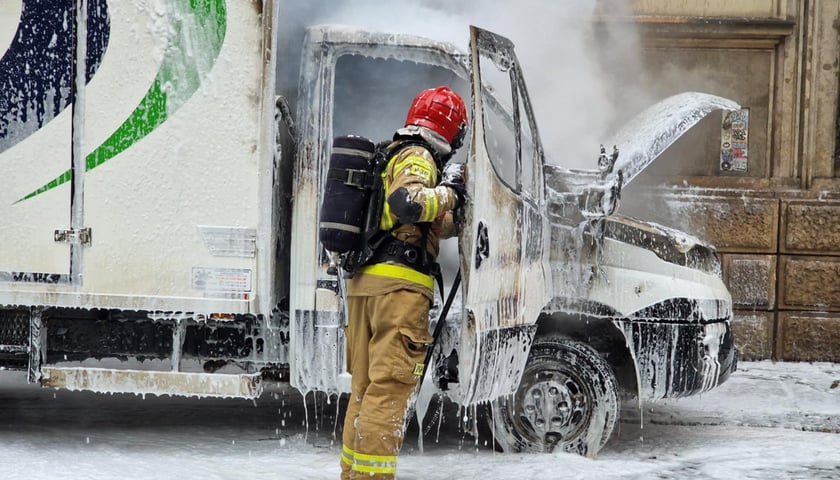 Strażak dogasza pożar samochodu dostawczego, piana gasząca, kabina samochodu