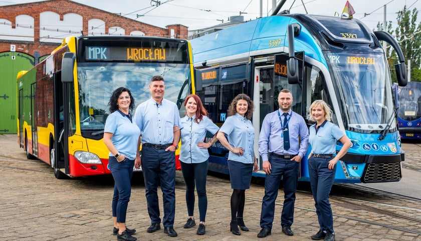 Pracownicy MPK Wrocław na tle autobusu i tramwaju