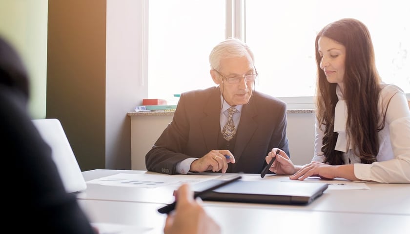 Młoda kobieta rozmawia w biurze ze starszym mężczyzną. Zdjęcie ilustracyjne