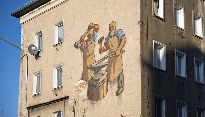 <p>Mozaika na elewacji domu nr 11 przy ul. Ustronie pokazuje dw&oacute;ch kowali przy pracy</p>