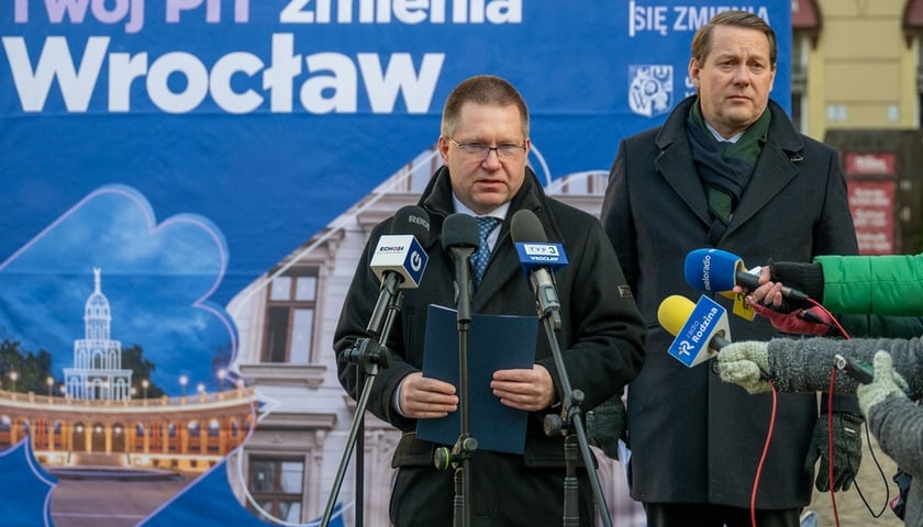 Skarbnik Miasta Marcin Urban i wiceprezydent Wrocławia Michał Młyńczak na tle bilbordu „Twój PIT zmienia Wrocław"