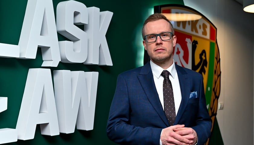 Michał Mazur - nowy prezes Śląska Wrocław na tle klubowego logo