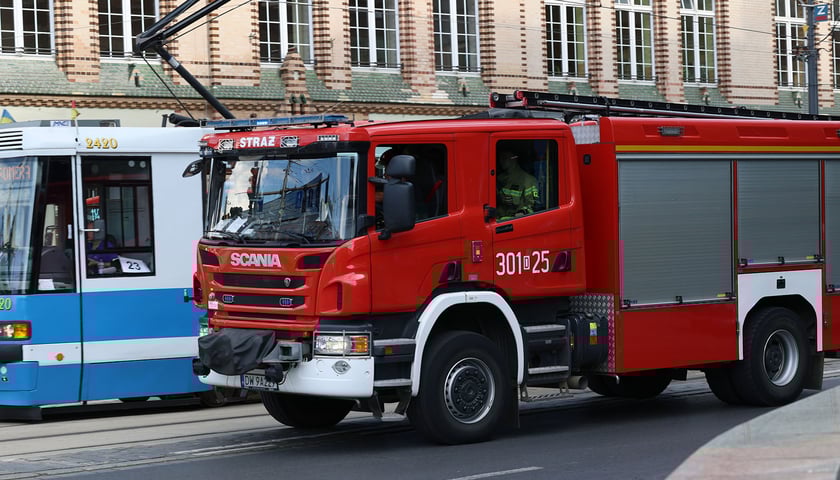 Wóz strażacki na ulicy, w tle tramwaj, zdjęcie ilustracyjne