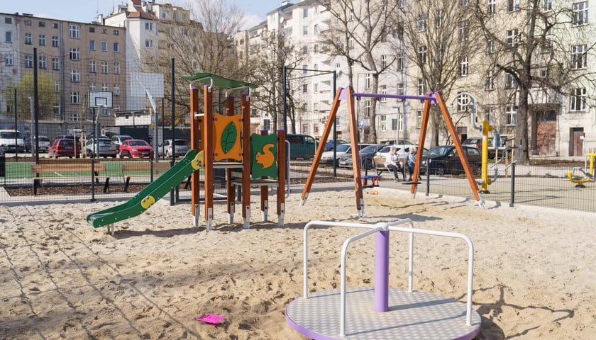 Plac zabaw, w tle boisko i ławki na wyremontowanym podwórku