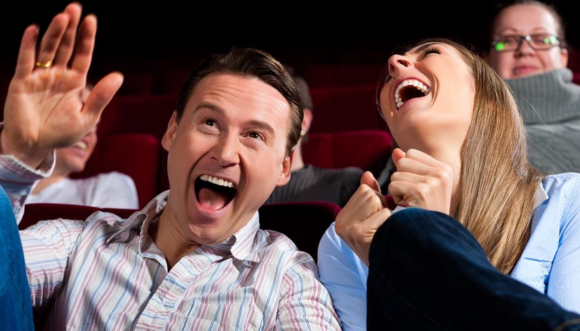 Para zaśmiewająca się w kinie, w tle dwie inne osoby