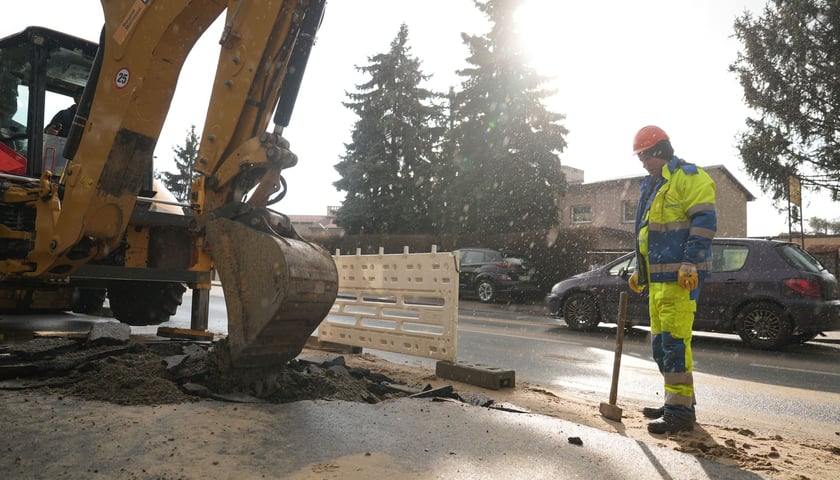 Awaria wodociągowa. Na zdjęciu pracownik MPWiK Wrocław i koparka. Zdjęcie ilustracyjne