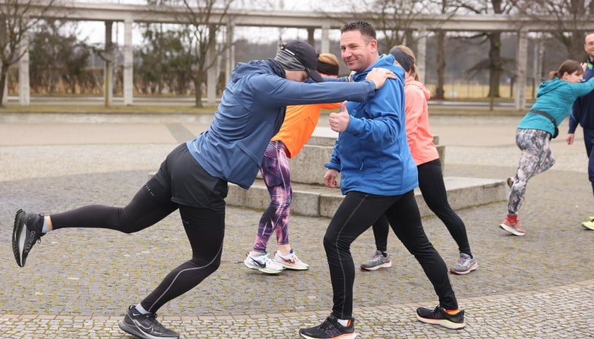 Dwie osoby na treningu na Olimpijskim, jedna trzyma drugą za barki i odchyla nogę do tyłu (1 marca 2025)