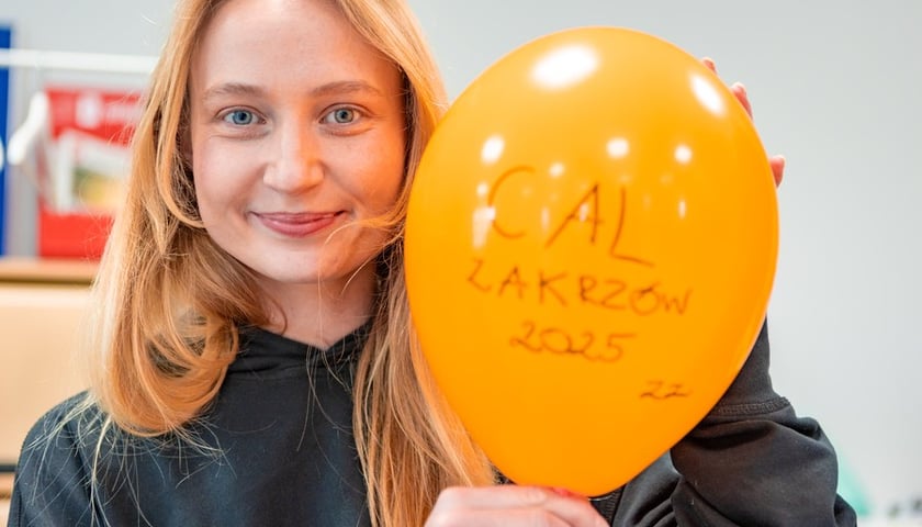 Młoda uśmiechnięta dziewczyna z żółtym balonem z napisem CAL Zakrzów 2025