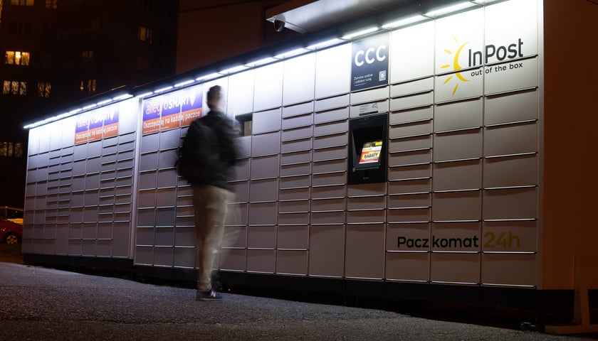 Paczkomat InPost, człowiek nadający paczkę nocą na osiedlu