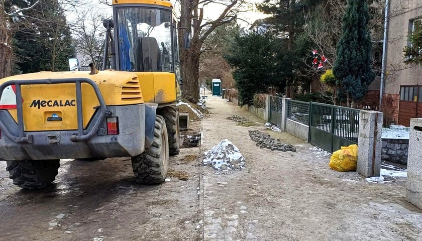 Remont chodnika na ulicy Odkrywców, z lewej żółta koparka 