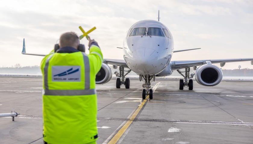 Pracownik lotniska we Wrocławiu, w tle samolot, zdjęcie ilustracyjne