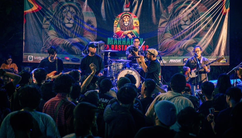 Koncert zespołu reggae. Na zdjęciu widać muzyków, po sceną stoi publiczność. Zdjęcie ilustracyjne