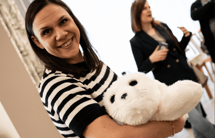 Kamila Szczęśniak, terapeutka zajęciowa z Domu Pomocy Społecznej przy ul. Mącznej trzyma na rękach maskotkę białą fokę, oddającą nastrój pacjenta