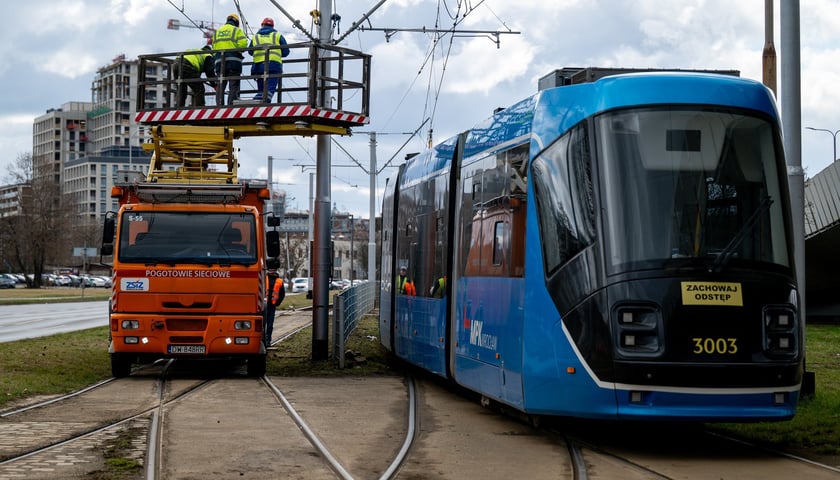 Wóz pogotowia sieciowego, pracownicy naprawiają trakcję, tramwaj