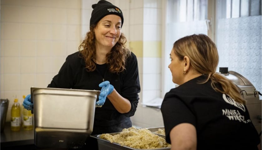 <p>Fundacja Mniej Więcej. Na zdjęciu dwie kobiety przygotowujące posiłek.</p>