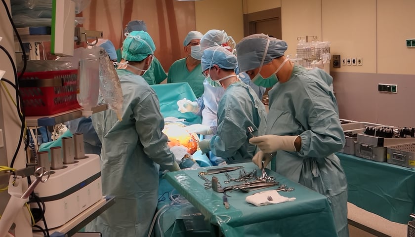 Na zdjęciu sala operacyjna. Przy stole operacyjnym stoi kilka osób w fartuchach