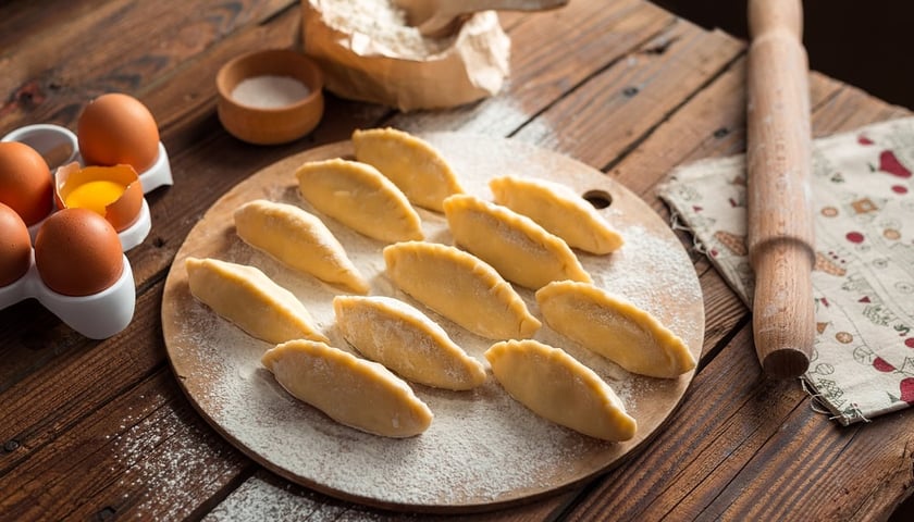 Pierogi. Na zdjęciu widać też - po lewej stronie - jajka, po prawej wałek do rozwałkowania ciasta.