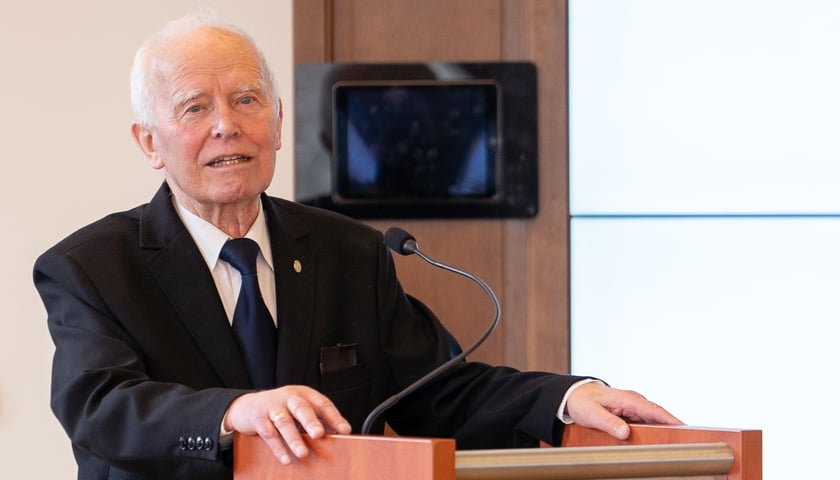 Prof. Andrzej Wiszniewski. Na zdjęciu przy mównicy stoi starszy mężczyzna w garniturze