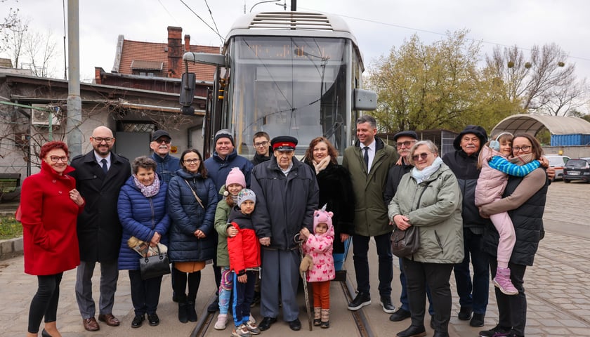 Roman Kroczak - stuletni motorniczy w otoczeniu rodziny na tle tramwaju