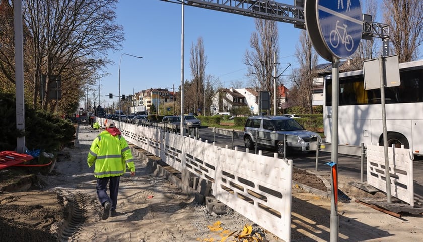 Chodnik przy Ślężnej w przebudowie, znak drogowy, robotnik w żółtej kamizelce i w kasku
