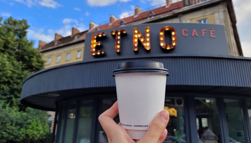 Na zdjęciu kubek z kawą, za nim pierwszy lokal sieci kawiarni Etno Cafe we Wrocłaiwu.